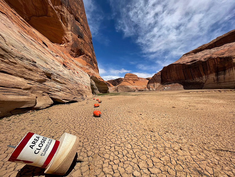 Buoys sit on dry, cracked sand where Lake Powell once was.
