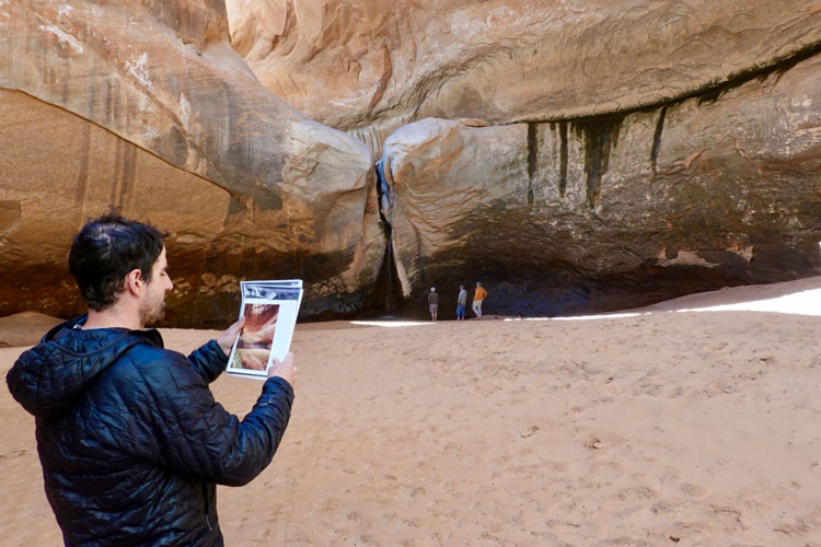 A man stands in Glen Canyon and looks at photos of what the canyon looked like previously.