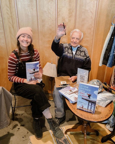 Ayja and her grandfather selling and signing book copies.