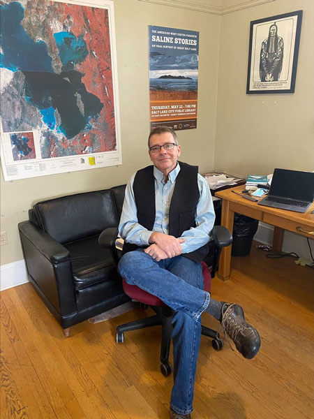 Greg Smoak sitting in a chair by his desk in the American West Center.