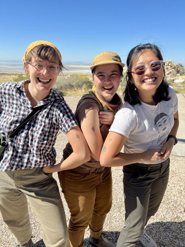 Students pose with brine shrimp tattoos on their arms with Great Salt Lake in the background.