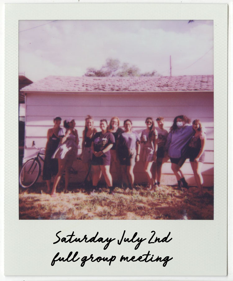 Group of artists stands in front of a building outside in a field of grass.