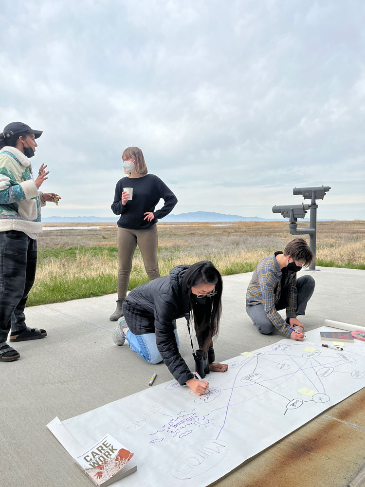 Working group members talking and taking notes on a big sheet of paper outside at Farmington Bay.